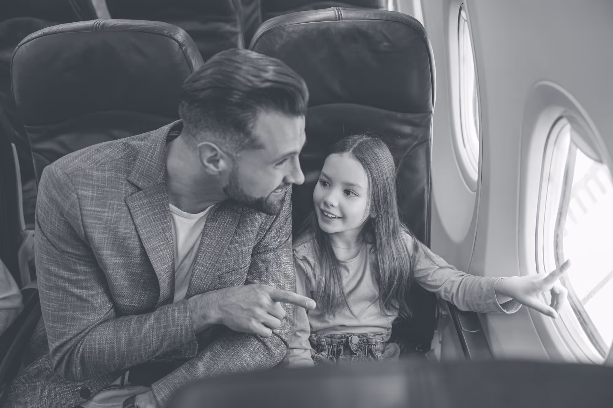 A father showing his daughter something out of a plane window